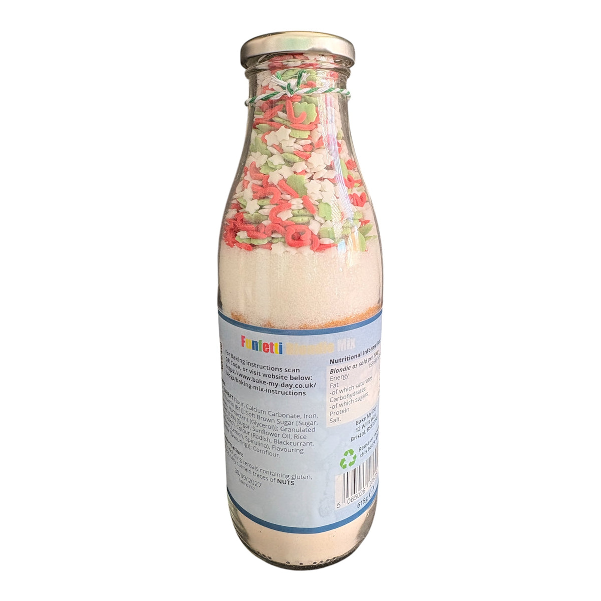 A glass bottle filled with a layered dry mix, featuring a colorful top layer with red, green, and white pieces, and a white lower layer. The bottle has a blue and white label with the brand name 'Fenoli' visible, and is photographed against a plain white background.