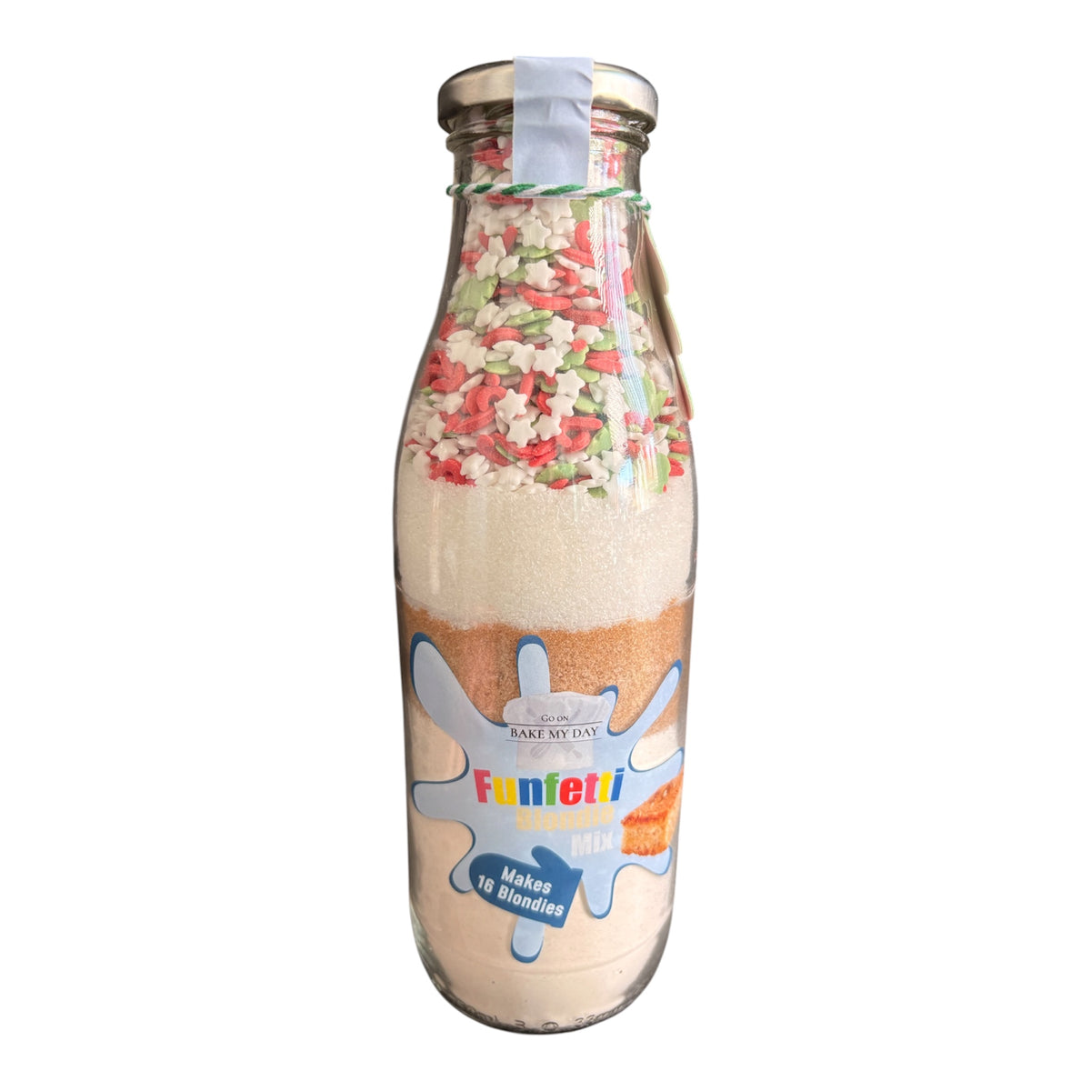 A glass milk bottle filled with layered ingredients for making candy, topped with red, green, and white sprinkles. The bottle features a colorful label that reads 'Funfetti Makes 10 Bundles' and is sealed with a silver metal cap.