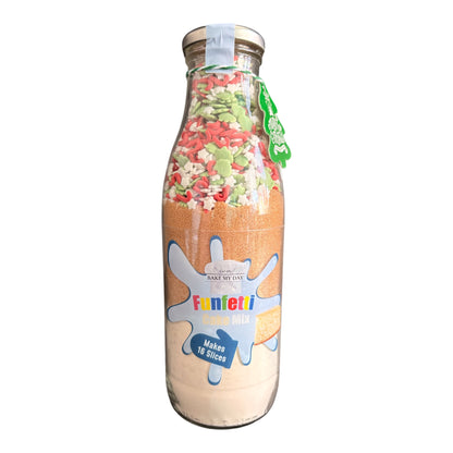 A glass milk bottle filled with Funetti Christmas Nut Mix, featuring a colorful sprinkle layer on top and a beige powder base, complete with a gold screw cap and a green hanging tag.