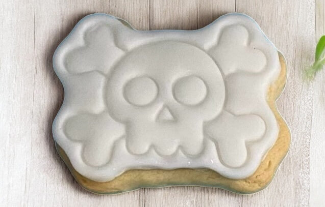 Skull & Cross Bones Paint Your Own Cookie – skull and crossbones-shaped iced biscuit with edible paint palette and brush, fun and creative kids’ Halloween baking activity or party treat.